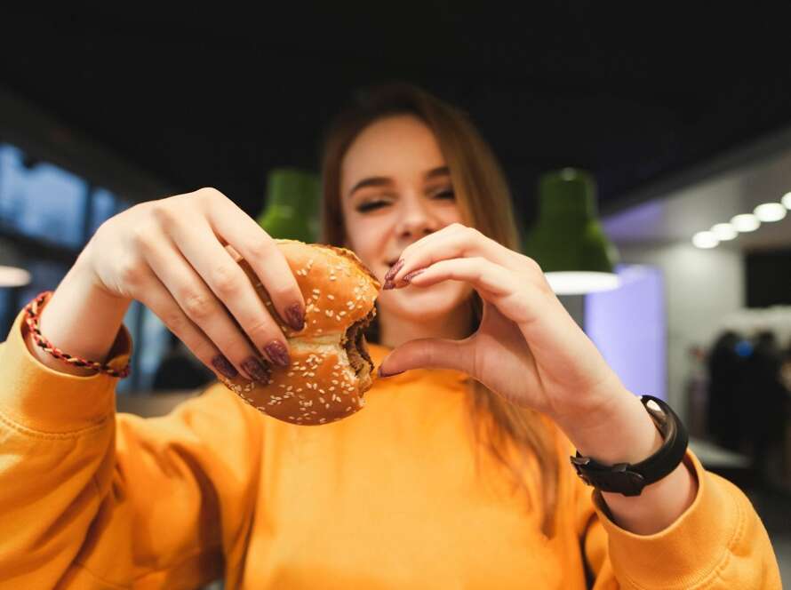 Joven feliz comiendo hamburguesa
