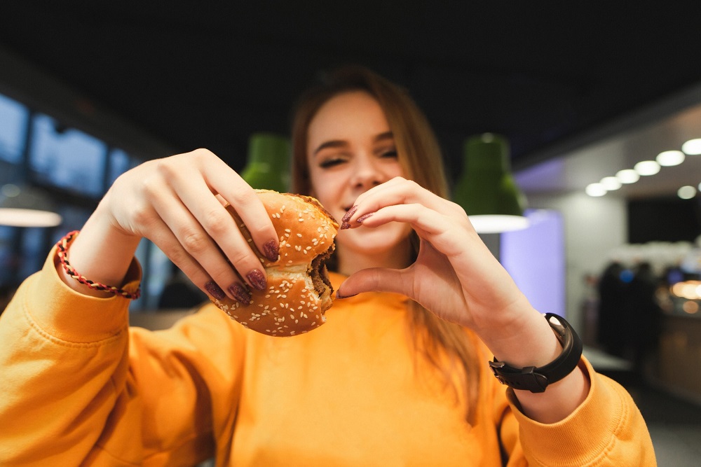 Joven feliz comiendo hamburguesa
